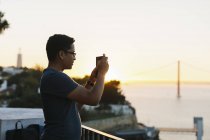 Людина фотографується зі смартфоном під час заходу сонця — стокове фото