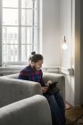 Fokussierter junger Mann nutzt Tablet-PC im Sitzen an der Lampe — Stockfoto