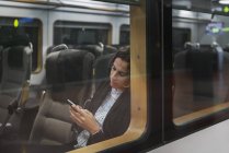 Woman using smart phone on train — Stock Photo