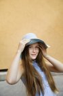 Portrait of teenage girl wearing hat and smiling at camera in parking lot — Stock Photo