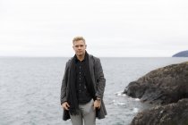 Young man wearing gray coat by Vattern lake in Stora Lund Nature Reserve, Sweden — Stock Photo