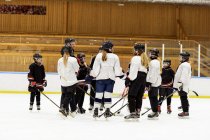 Mädchen hören ihrem Trainer beim Eishockey-Training zu — Stockfoto