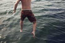 Чоловік стрибає в море, вибірковий фокус — стокове фото