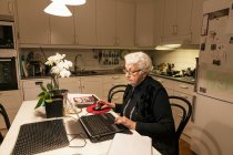 Mulher sênior usando laptop na cozinha — Fotografia de Stock