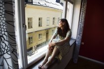 Femme regardant par la fenêtre, mise au point sélective — Photo de stock