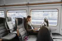 Giovane donna che viaggia in treno utilizzando il computer portatile — Foto stock
