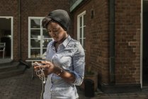 Улыбающаяся женщина с помощью смартфона вне дома — стоковое фото