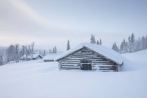 Cabanes en rondins recouvertes de neige — Photo de stock