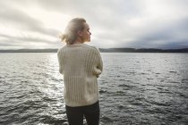 Giovane donna in piedi accanto al lago — Foto stock