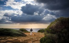 Hombre paseando perro en Cap Blanc al atardecer en Mallorca, España - foto de stock