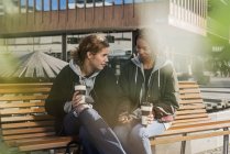 Teenage girls using smart phone on bench — Stock Photo
