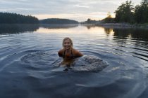 Femme dans le lac Skiren au coucher du soleil en Suède — Photo de stock