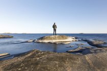 Чоловік стоїть на скелі біля моря, вибірковий фокус — стокове фото