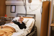 Старший чоловік лежить на лікарняному ліжку — стокове фото