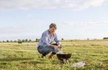 Woman crouching by brazier in field — Stock Photo