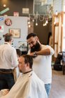 Peluqueros cortando el pelo de los clientes en la barbería - foto de stock