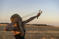 Teenage girl using sling shot in field — Stock Photo