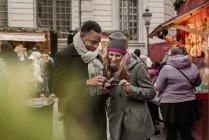 Couple using smart phone and smiling, selective focus — Stock Photo