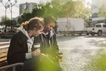 Девочки-подростки используют смартфон на скамейке запасных — стоковое фото