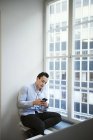 Young man using smart phone by window — Stock Photo
