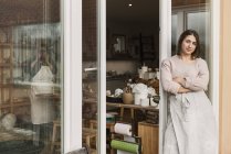 Mujer apoyada en la puerta del taller de cerámica - foto de stock