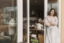 Woman leaning on door of pottery workshop — Stock Photo