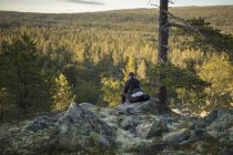 Uomo seduto sulla roccia nella Riserva Naturale di Tofsingdalen in Svezia — Foto stock