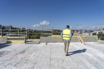 Trabajador de la construcción en el techo del edificio incompleto - foto de stock
