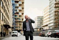 Homme d'affaires barbu souriant parlant par téléphone intelligent en ville — Photo de stock