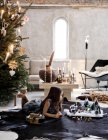 Menina deitada ao lado do presépio e árvore de Natal na sala de estar — Fotografia de Stock