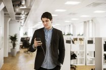 Junger Mann mit Smartphone im Büro — Stockfoto