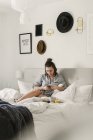 Junge Frau benutzt Smartphone im Bett — Stockfoto