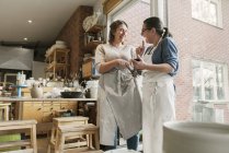 Женщины используют смартфон в мастерской по гончарному делу — стоковое фото