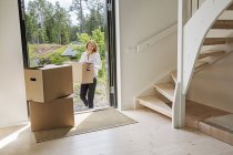 Mujer que lleva la caja de cartón en casa - foto de stock