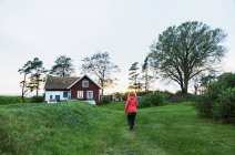 Женщина, идущая в поле за домом — стоковое фото