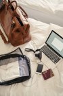 Ordinateur portable, sac et différentes choses sur le lit, mise au point sélective — Photo de stock