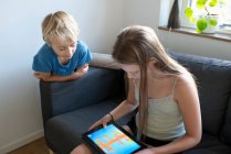 Мальчик и девочка смотрят на планшетный компьютер дома — стоковое фото