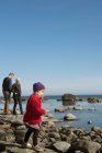 Батьки з дочкою стоять на скелях біля моря. — стокове фото