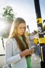 Teenage girl texting via smartphone on street. - foto de stock