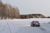 Coche que conduce por la carretera rural nevada en invierno - foto de stock