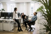 Compañeros de trabajo hablando en el escritorio, enfoque selectivo - foto de stock