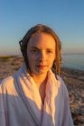 Ritratto di ragazza in accappatoio sulla spiaggia al tramonto — Foto stock