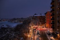 Здания и автомобили, покрытые снегом ночью в Стокгольме, Швеция — стоковое фото