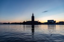 Silueta de edificios por mar al atardecer en Estocolmo, Suecia - foto de stock