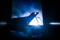 Piano in shadow on concert stage — Photo de stock