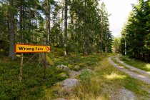 Wrong turn sign by rural road through forest — Stockfoto