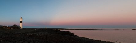 Lighthouse on coast at sunset — Fotografia de Stock