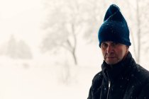 Portrait of mature man wearing beanie in snow — Fotografia de Stock