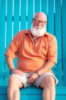 Портрет взрослого мужчины с бородой, сидящего на скамейке — стоковое фото