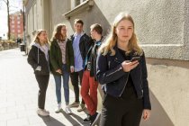 Jeune femme tenant un téléphone intelligent par ses amis à Stockholm, Suède — Photo de stock